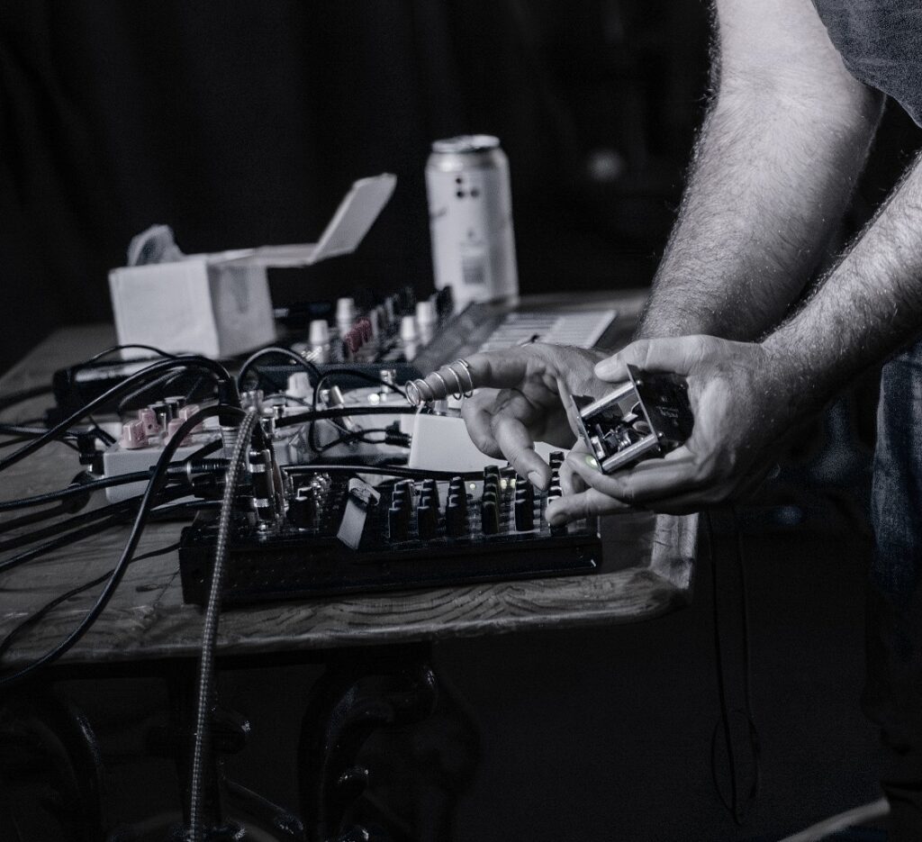 The hands of Sarram at work with pedals and electronics